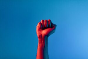 Raised arm with a clenched fist against the background of a blue sky